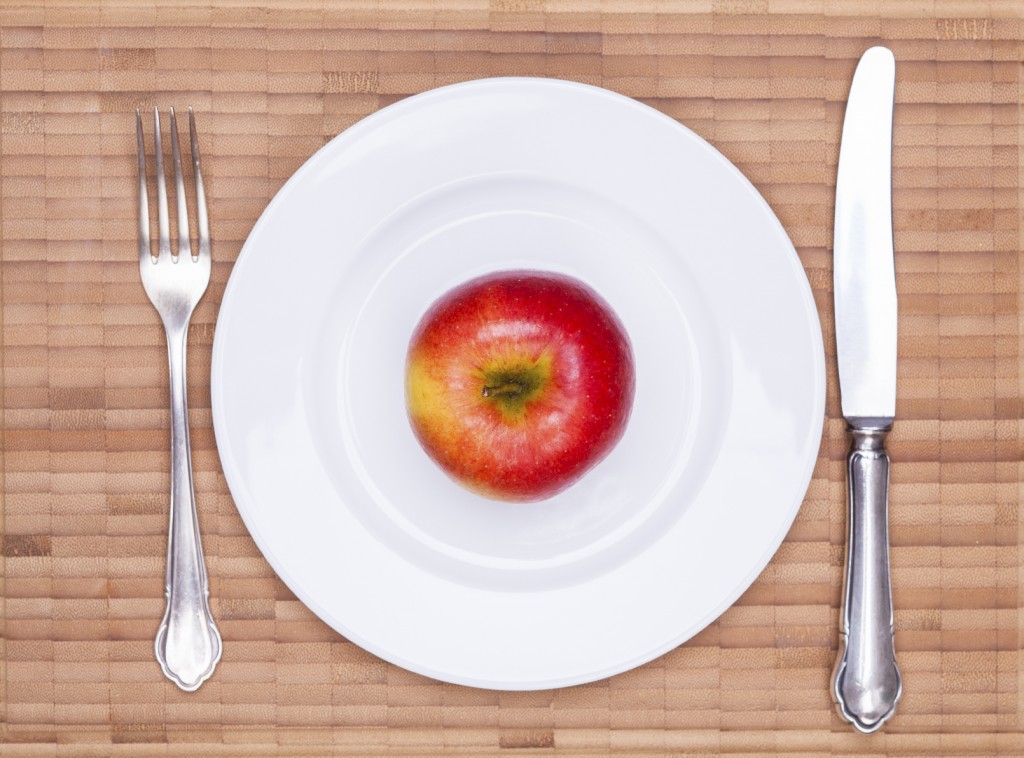 Juicy red apple on the white plate with vintage wooden table background