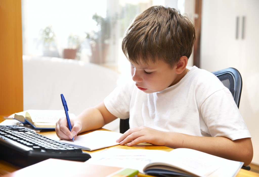 a boy writing at a desk