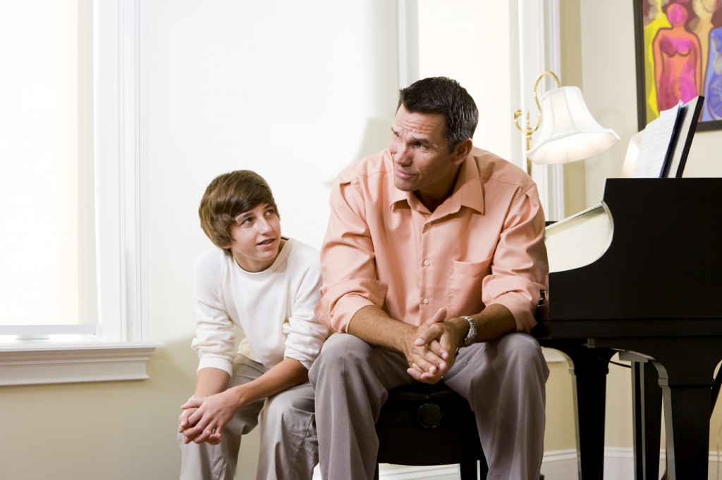 Father with teenage son sitting together at home conversing