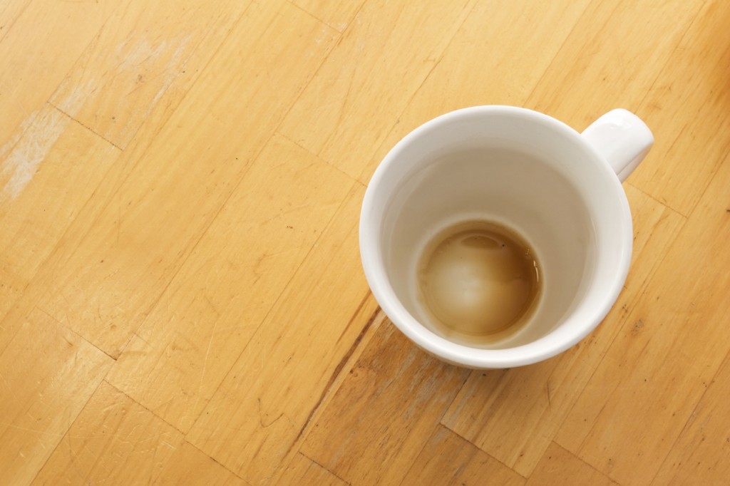 An empty cup of coffee viewed from above on a wooden table.