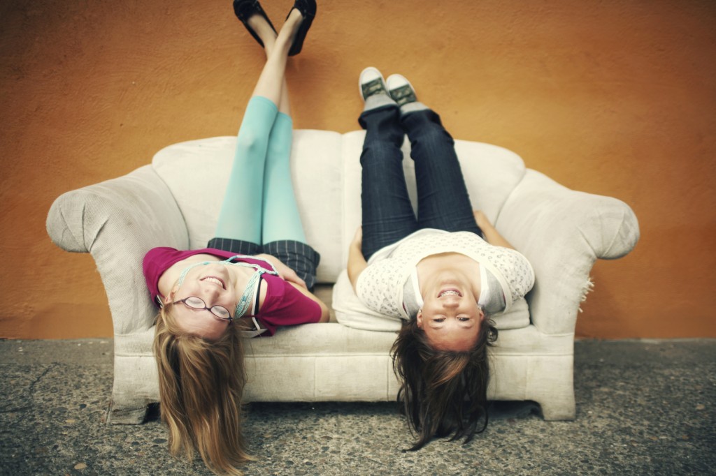 Teen Girls Upside Down on Orange Wall Couch