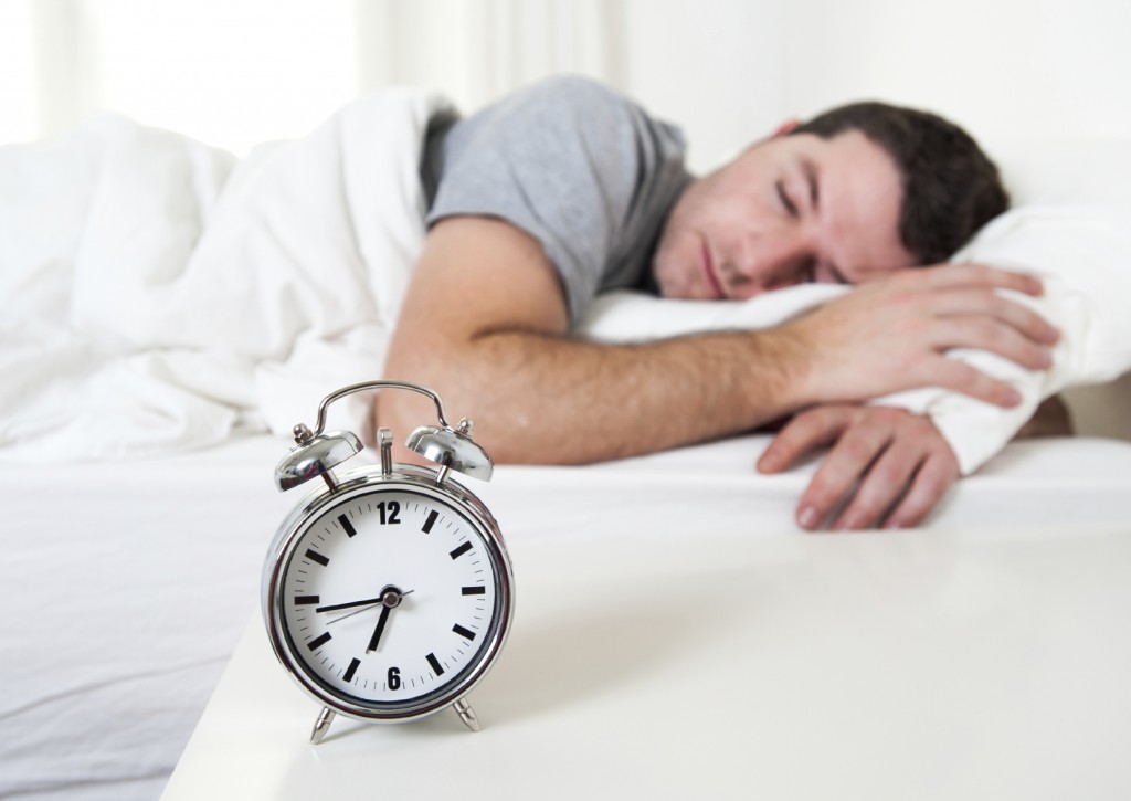 Young attractive man sleeping on bed early morning