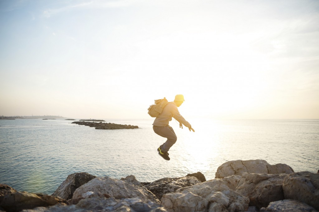 traveler jumping over rocks near the se