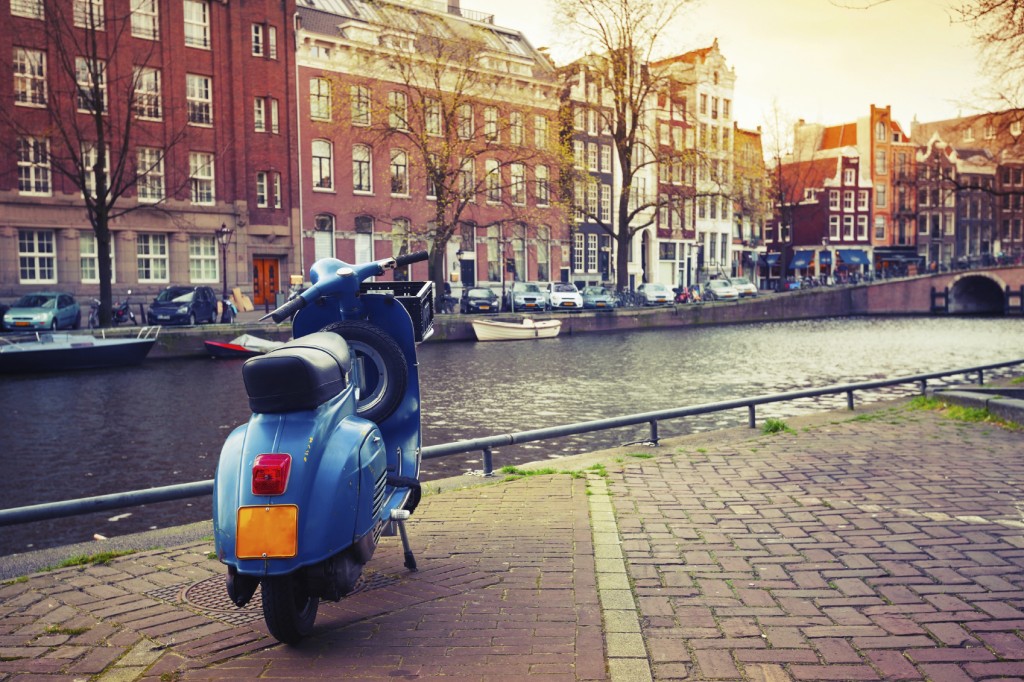 Blue scooter stands parked on the canal coast in Amsterdam. Inst