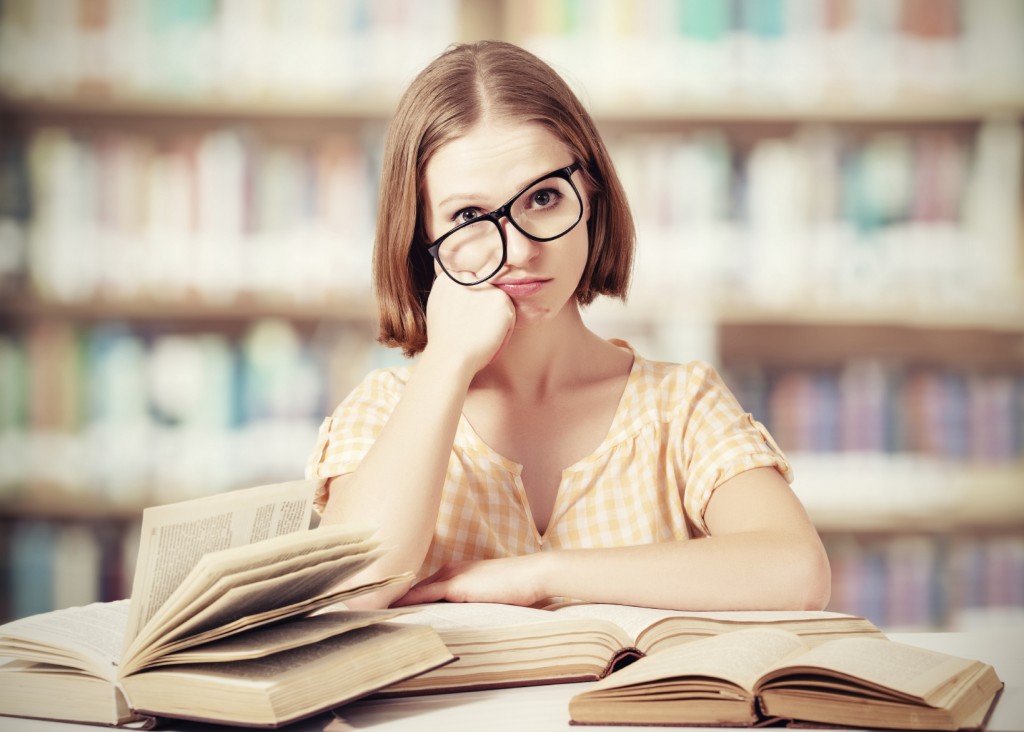 tired funny girl student with glasses reading books