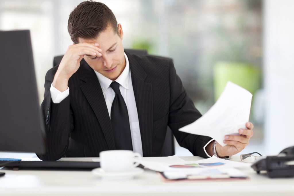 stressed businessman reading documents in office