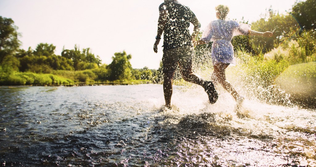 Happy couple running in shallow water. Summertime.