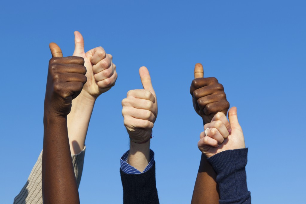 Multiracial Thumbs Up Against Blue Sky