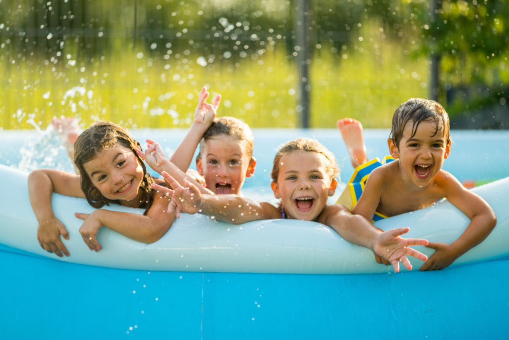 Siblings - four happy young kids in swimming pool