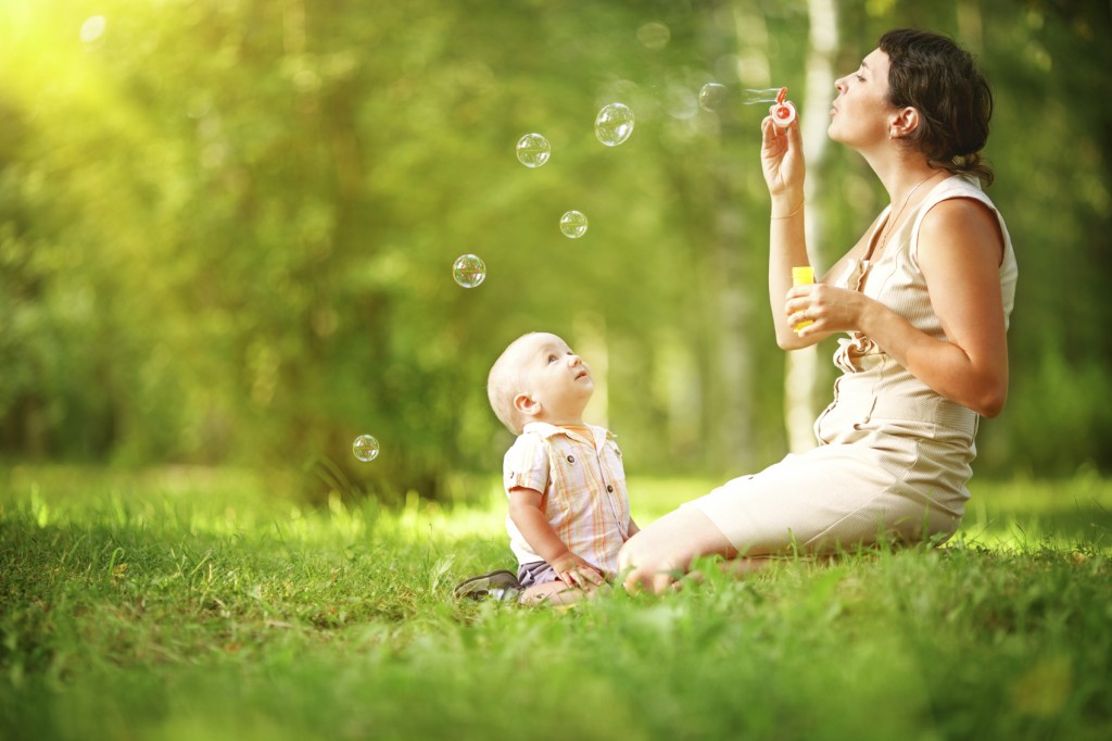 Mother and baby blowing bubbles in the park.
