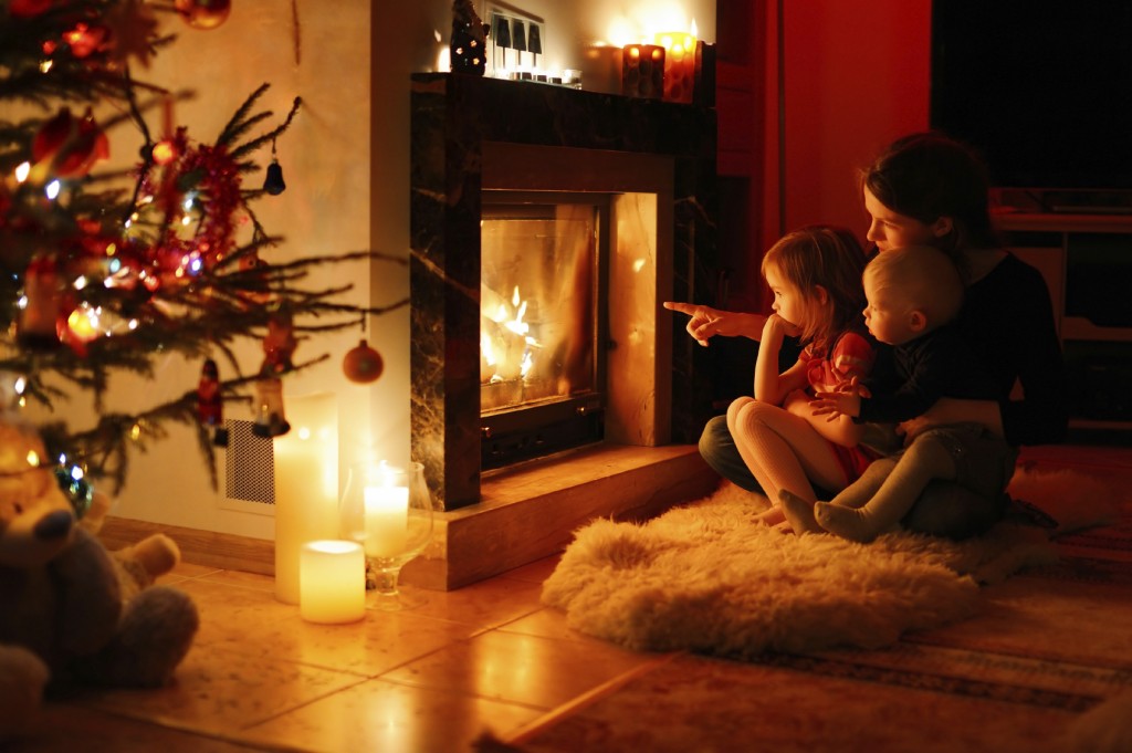 Young mother and her daughters by a fireplace on Christmas