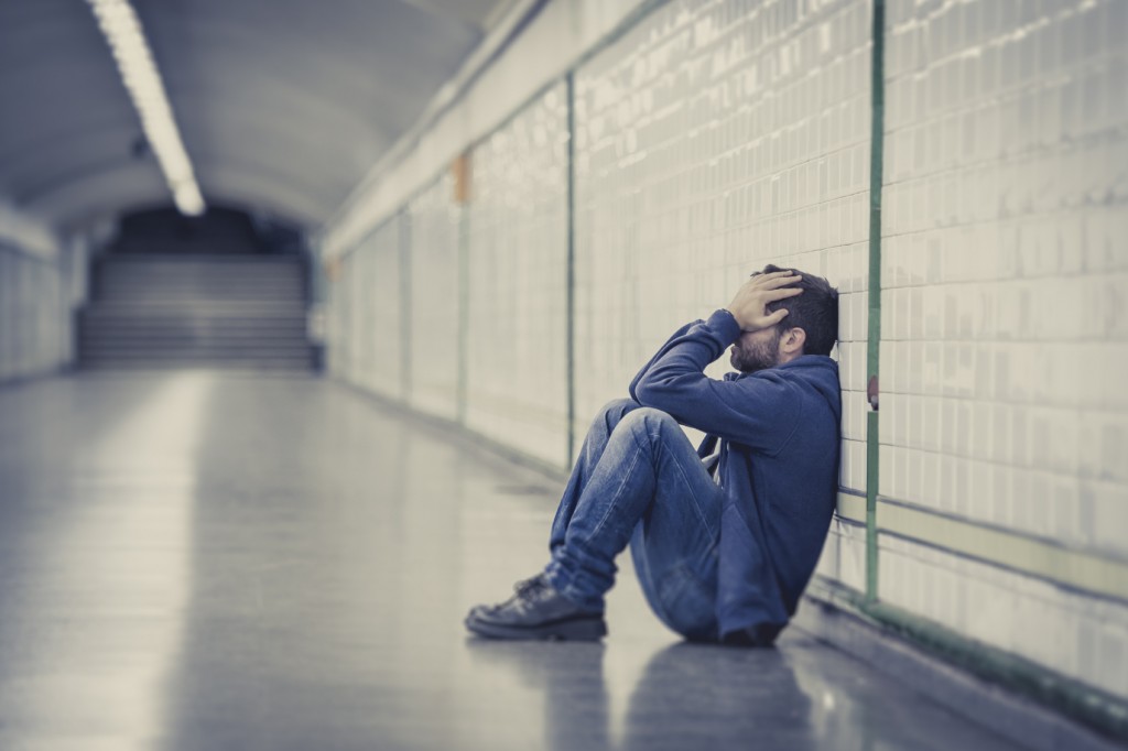 Sad young man sitting on ground street subway tunnel