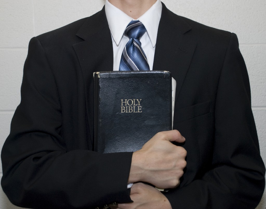 man in suit holding a Bible.