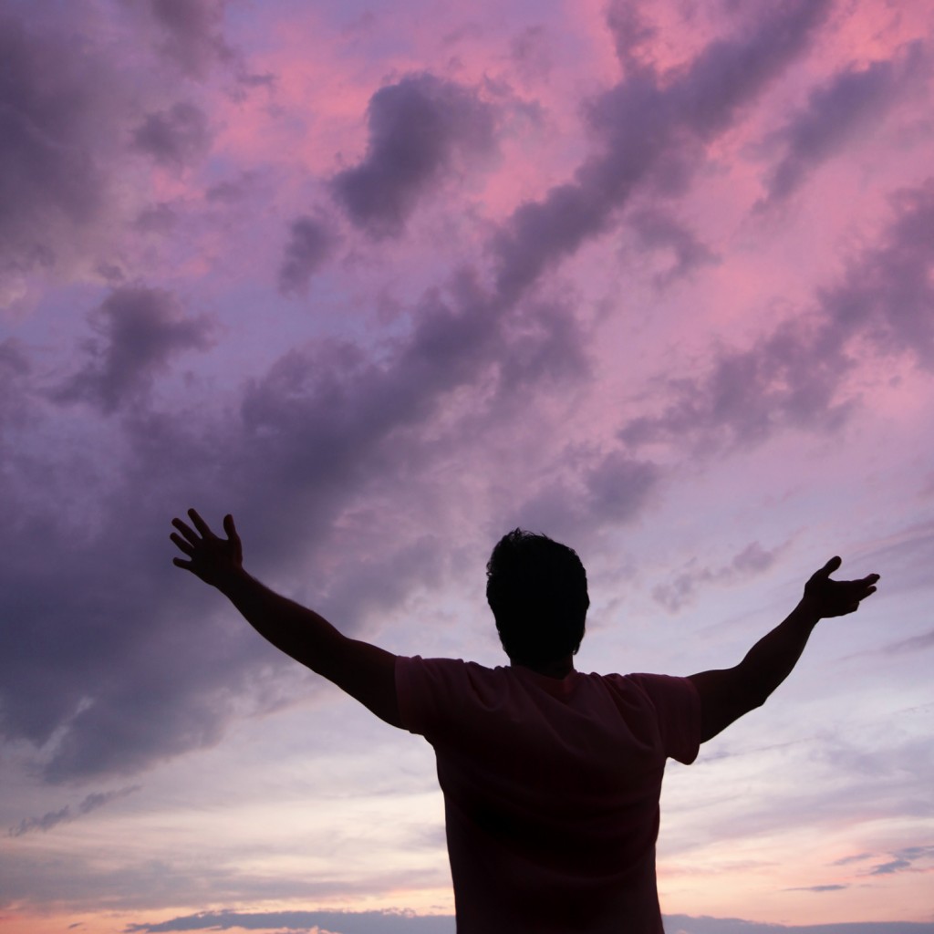 man with arms raised, Pink sunset in the background