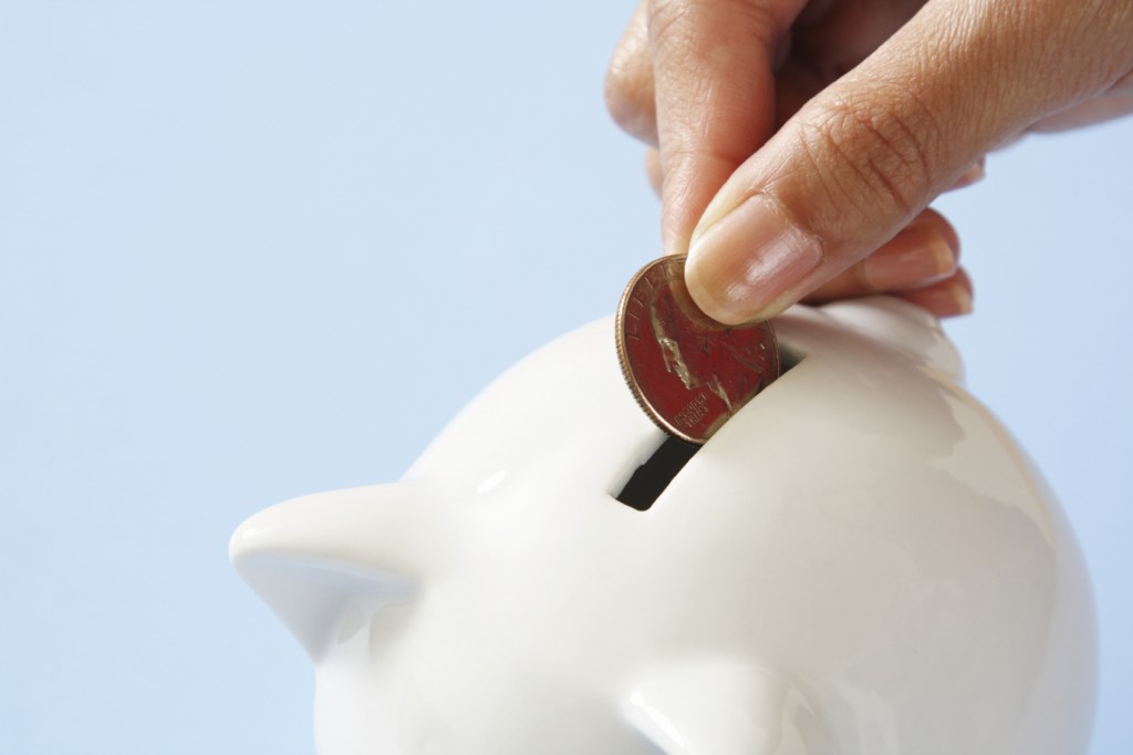 A woman saving a coin into a piggy bank