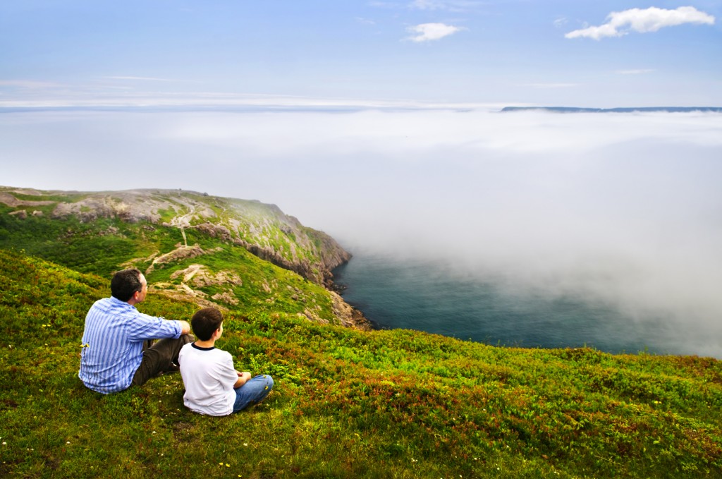Father and son looking at foggy ocean view in Newfoundland
