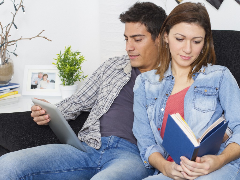 Young couple reading and using a tablet on a couch