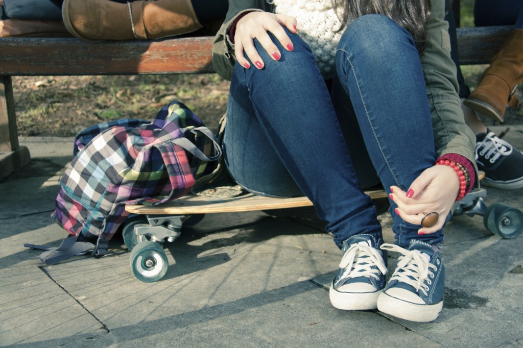 Legs of a girl sitting on a skateboard