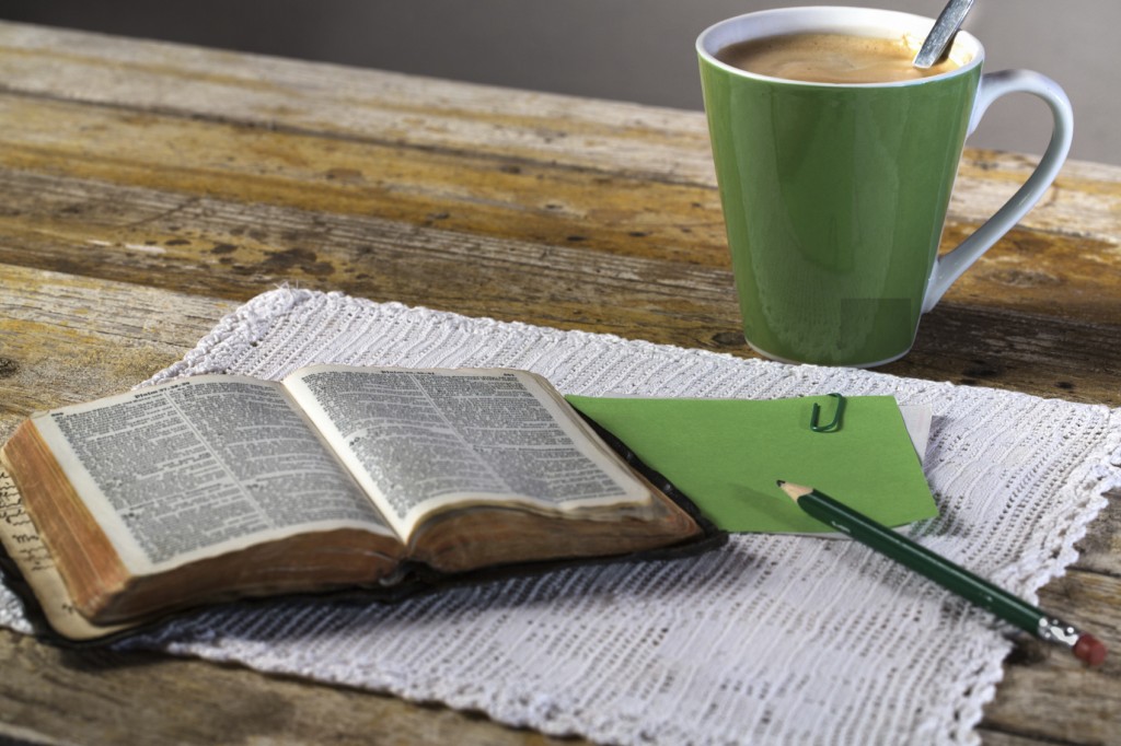 Reading in a bible, (book) drink a cup of coffee, write with the pencil