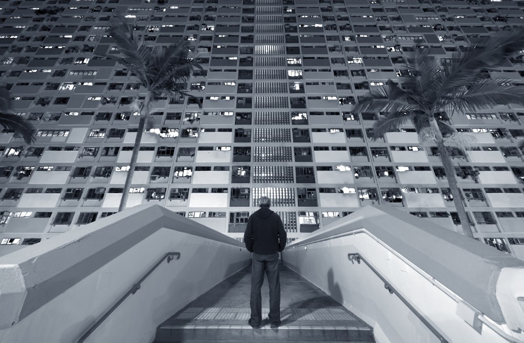 A man stand in front of a crowded residential building