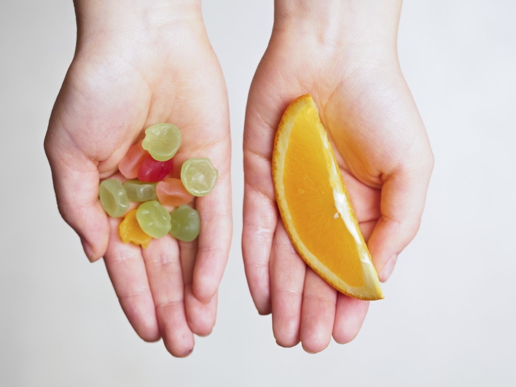 Candies and orange slice in the hands of a child