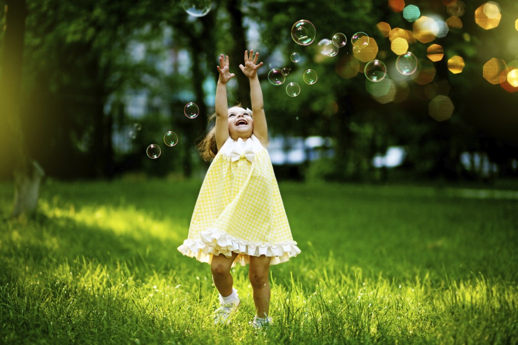 happy little girl playing with bubbles