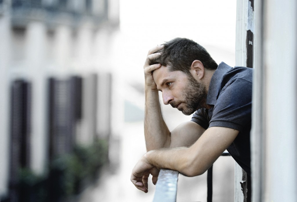 young man at balcony in depression suffering emotional crisis and grief