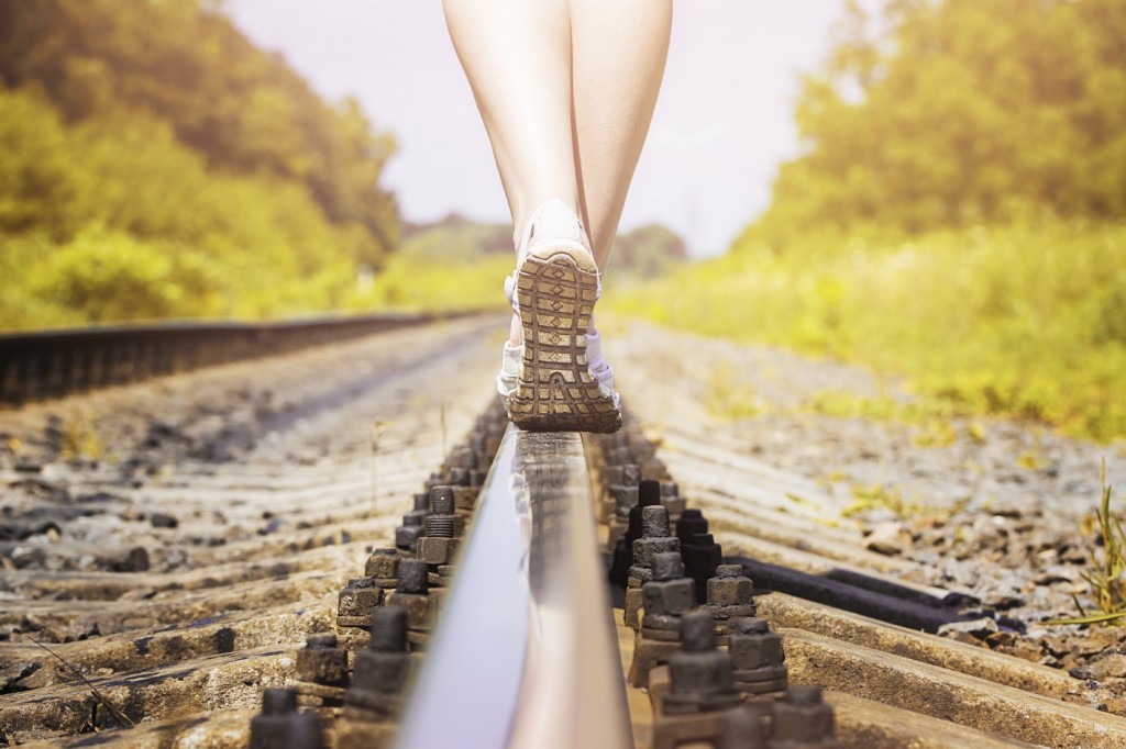 female legs in sneakers on the rail of the railway