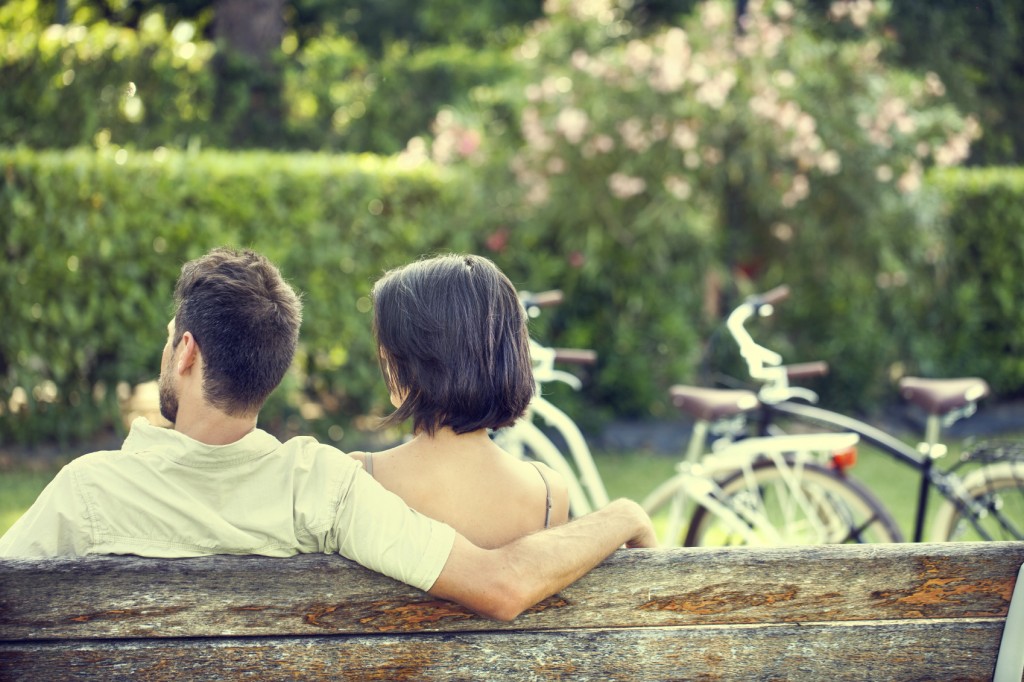Couple in love hugging each on a bench with bikes