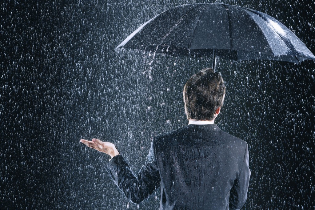 Rear View Of Businessman Under Umbrella In Rain