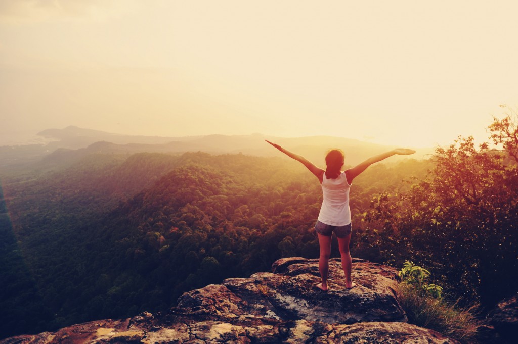 woman with arms raised on mountain peak
