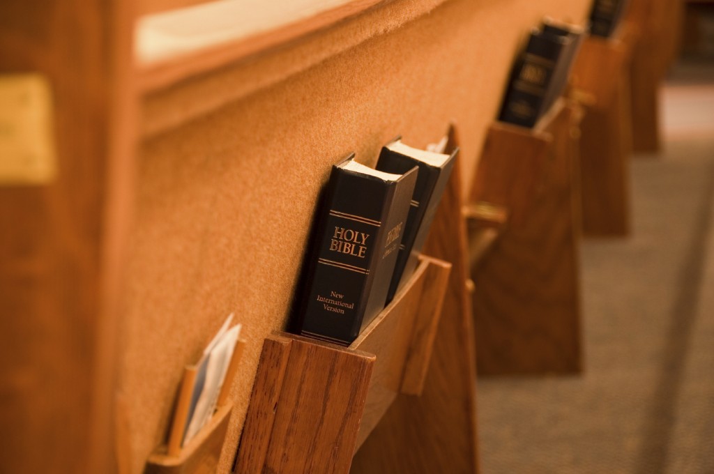 Holy Bible being held in a shelf on the back of a pew in a church