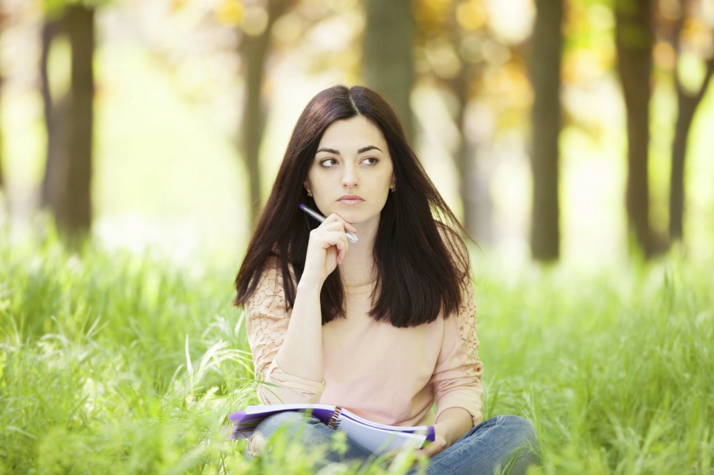Brunette girl with notebook in the park.