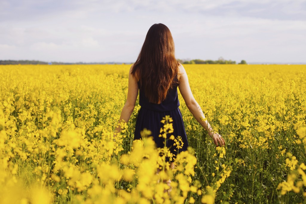 Girl enjoying rapeseed blooming on yellow meadow