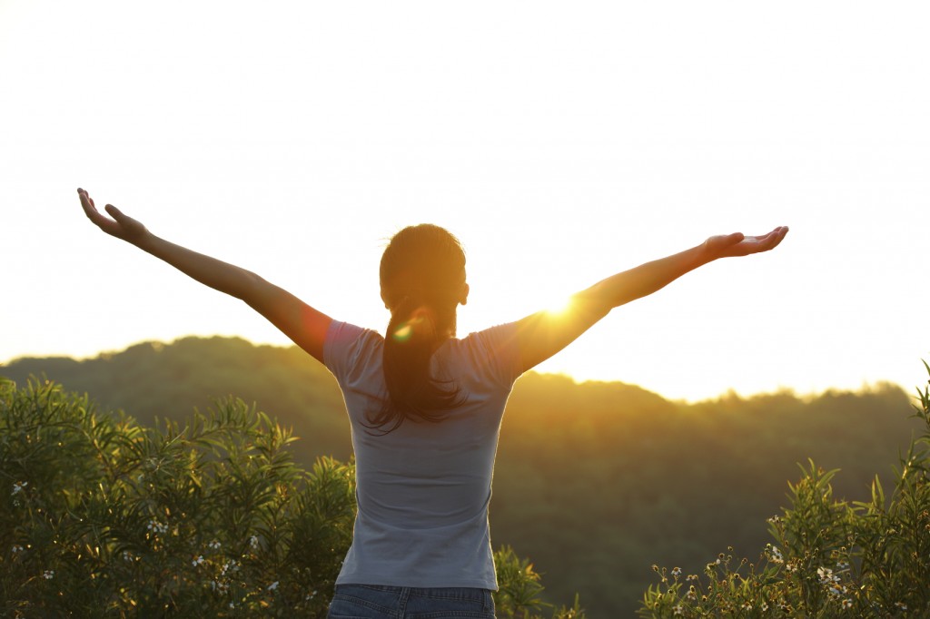 strong confident woman open arms to sunrise