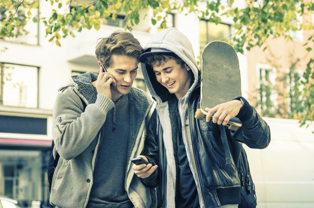 Young hipster brothers having fun with smartphone - Best friends