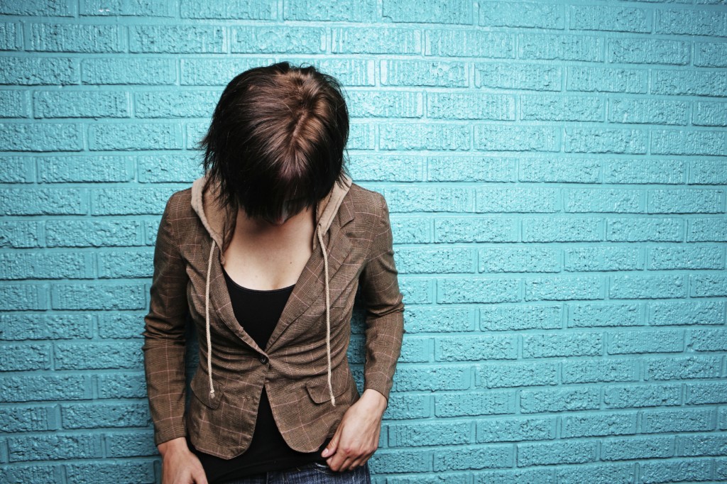 Shy Young Woman in Front of Bright Blue Wall