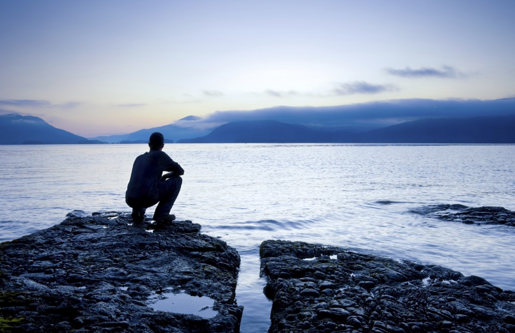 Man sitting on a small island watching the sunrise,