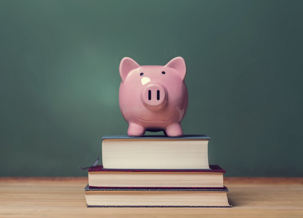 Piggy bank on top of books with chalkboard creating a cost of education theme