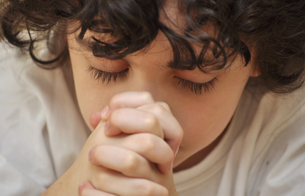 A young boys prays earnestly