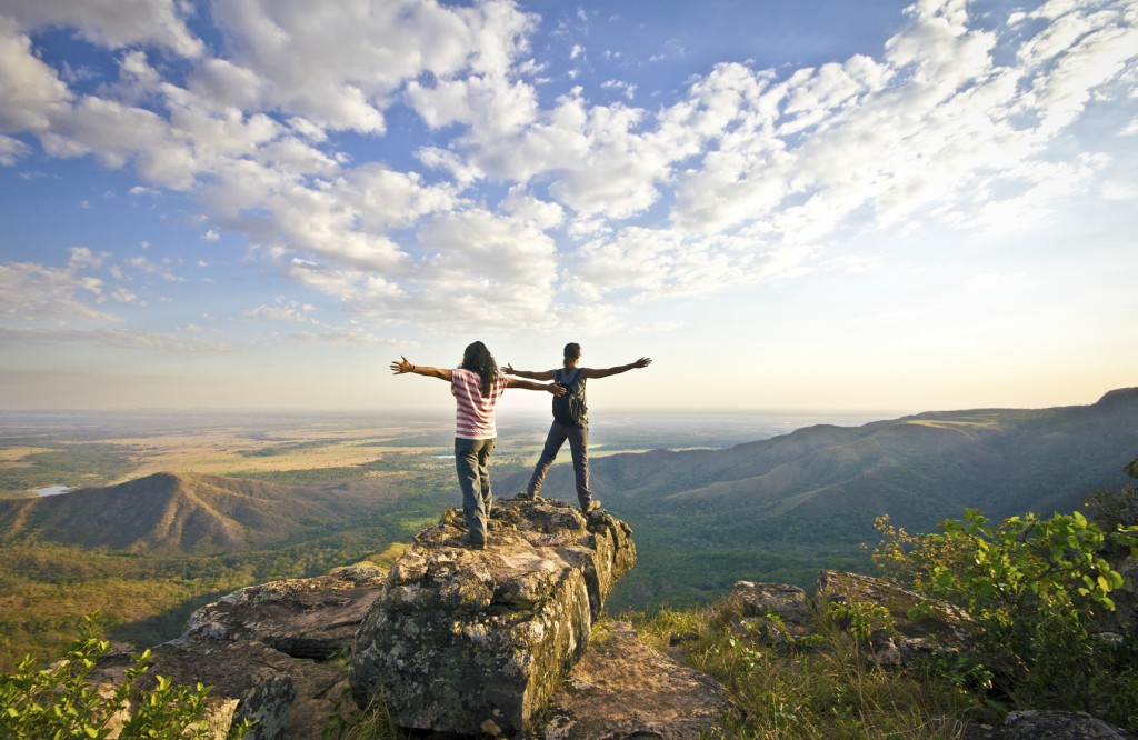 Two woman standing over mountain ridge.