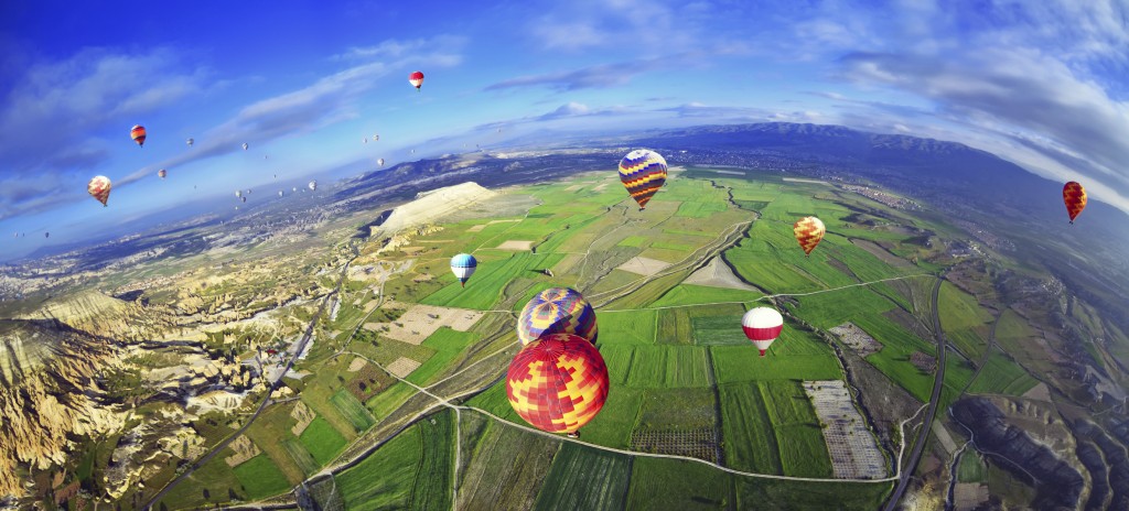 Colorful hot air balloon flying over rock landscape in blue sky