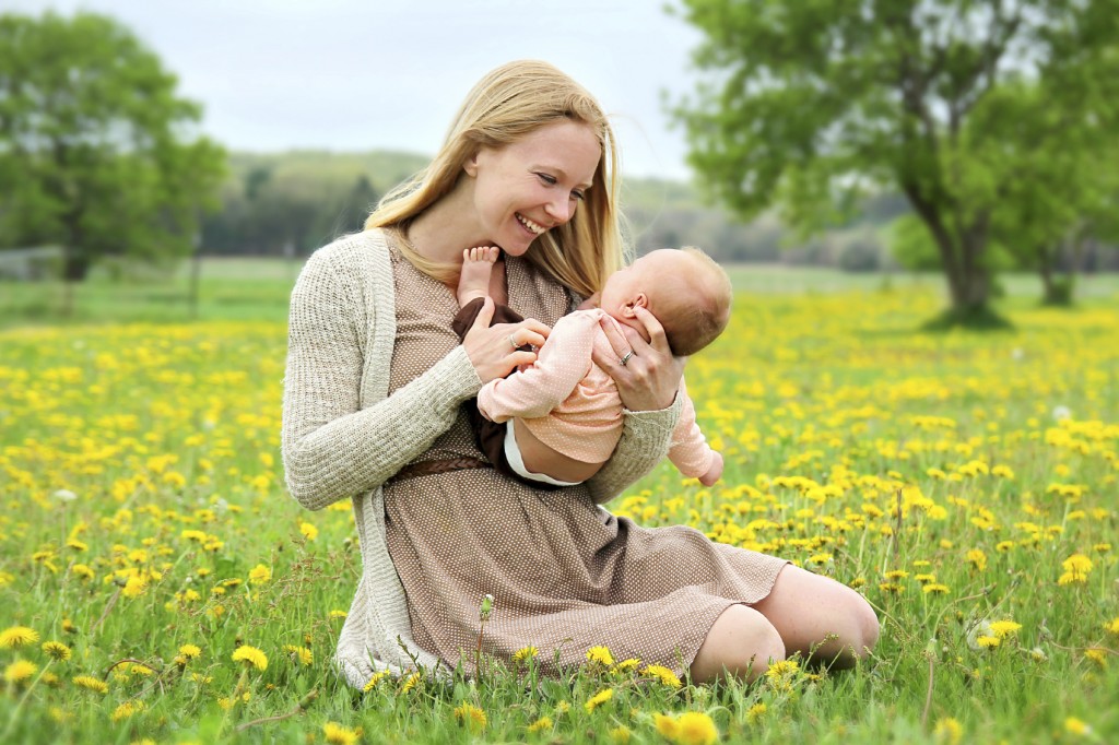 Happy Young Mother Playing with Newborn Baby Outside