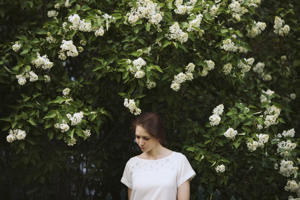 Woman standing next to a bush of white lilac