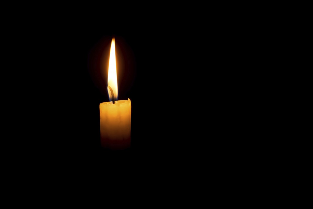 single candle in a dark room. concept of grief