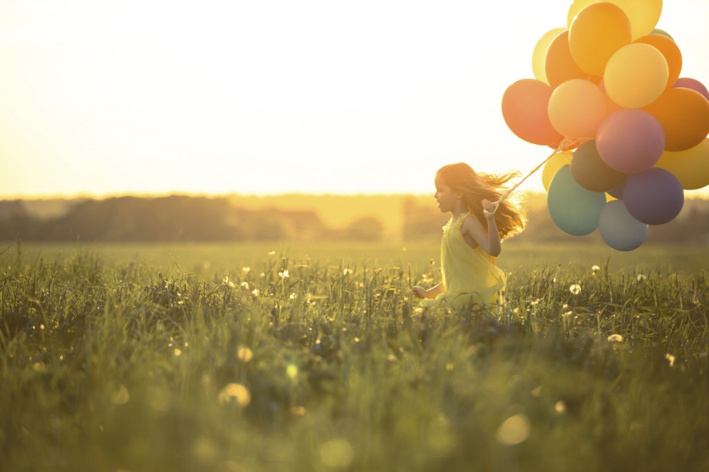 Happy girl with balloons in the field