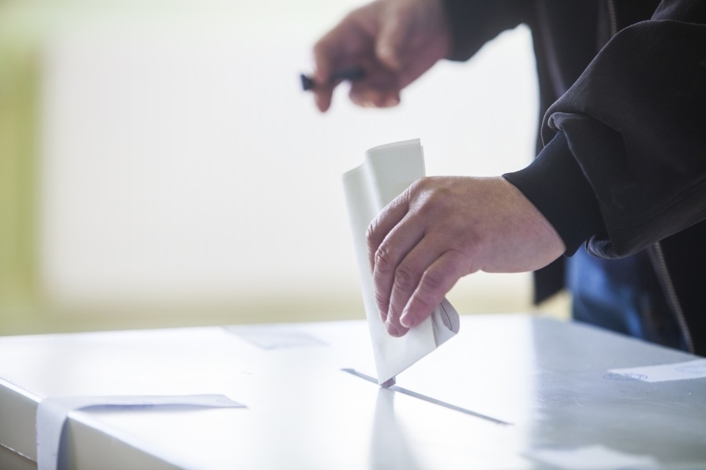 Hand of a person casting a ballot at a polling station during voting