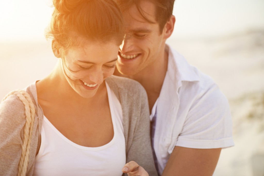 young couple sharing intimate moment smiling on beach