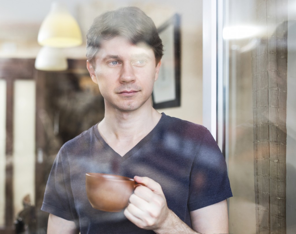 Man at home, drinking coffee or tea near window