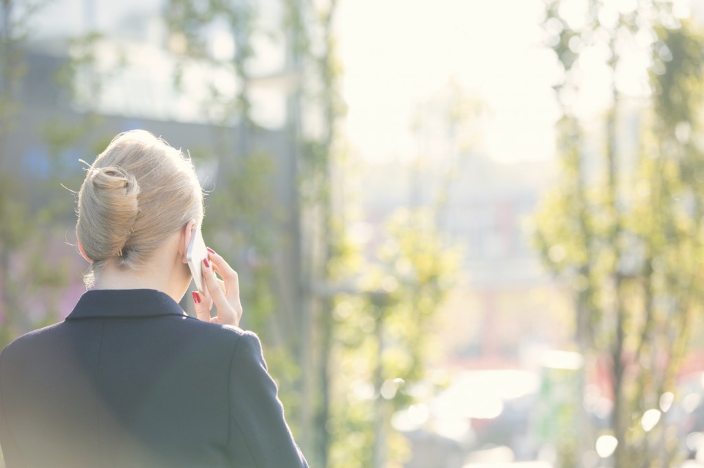 Rear view of businesswoman using cell phone on sunny day